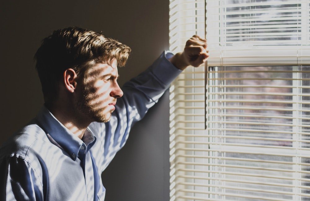 widower looking out window and sad